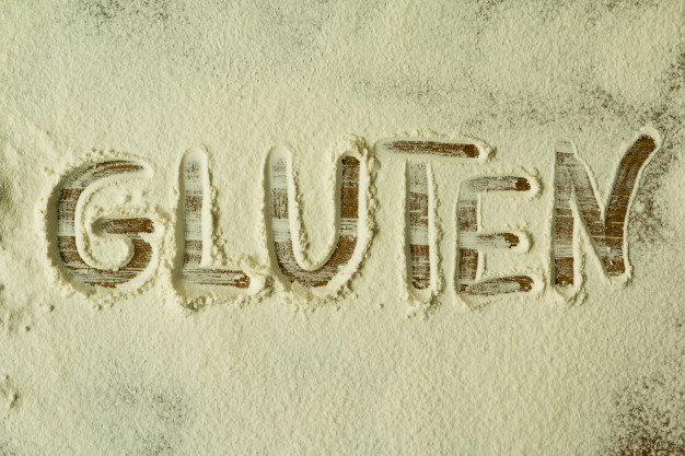 Le mot 'gluten' écrit dans de la farine de blé : représentant les intolérances alimentaires.