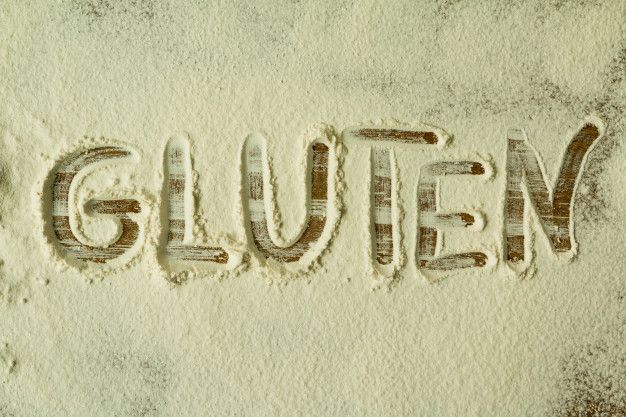Le mot 'gluten' écrit dans de la farine de blé : représentant les intolérances alimentaires.