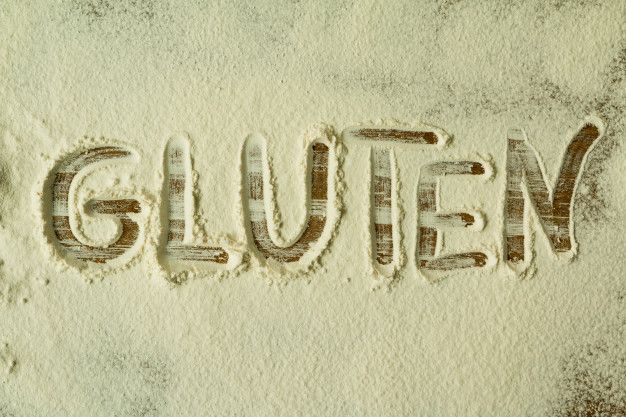 Le mot 'gluten' écrit dans de la farine de blé : représentant les intolérances alimentaires.
